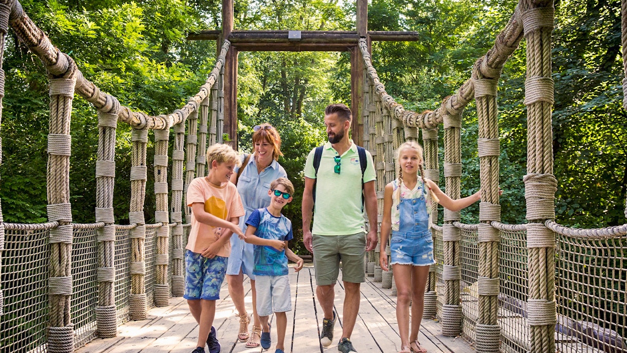 Family walking through Bellewaerde Park with roller coaster in background, Belgium.