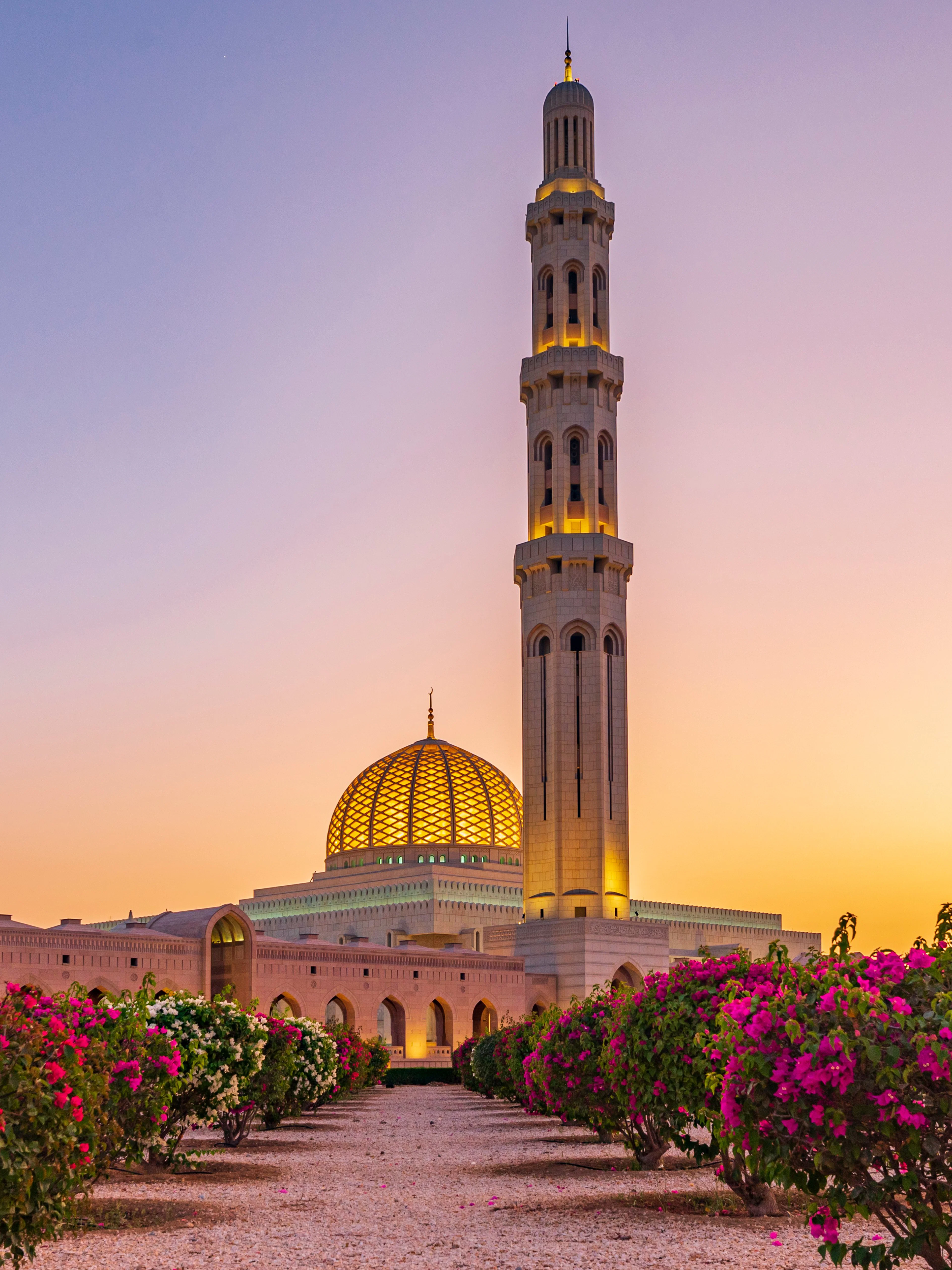 Sultan Qaboos Grand Mosque at sunset with floral gardens, Muscat, Oman.