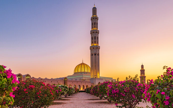 Sultan Qaboos Grand Mosque at sunset with floral gardens, Muscat, Oman.