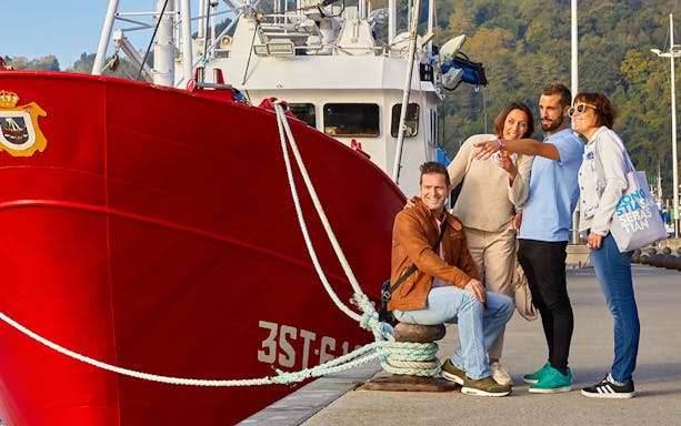 Group of tourists by a red boat in Zarautz during a guided tour from San Sebastian.