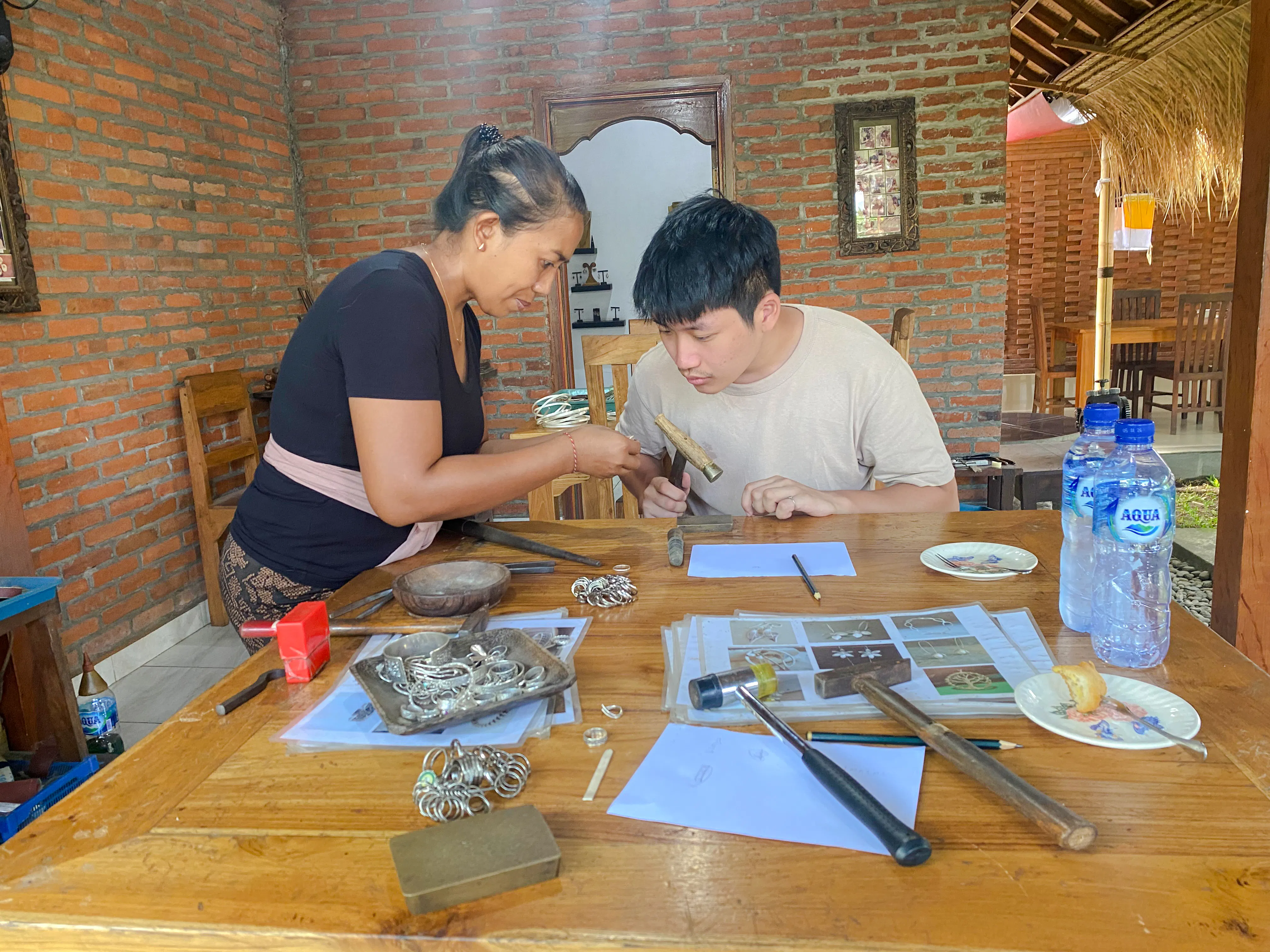Jewelry making class in Ubud, Bali, with instructor guiding a participant using tools.