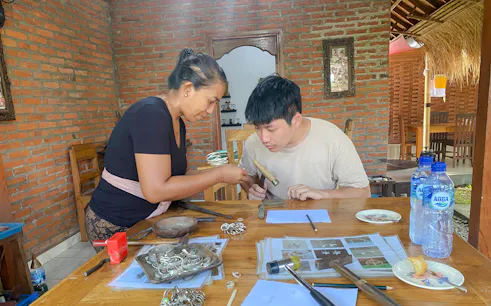 Jewelry making class in Ubud, Bali, with instructor guiding a participant using tools.