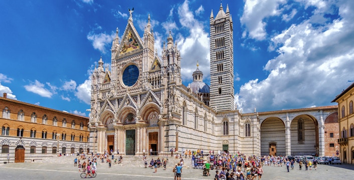Visitors exploring the piazza in front of Siena Cathedral, Italy.