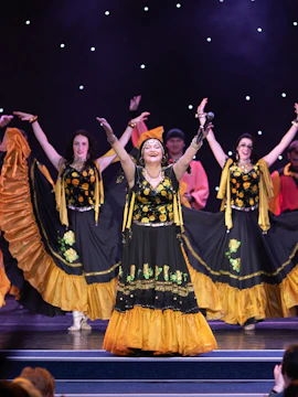 Flamenco dancers performing on stage in Valencia, wearing traditional black and yellow dresses.