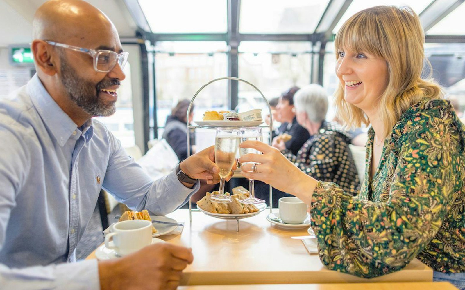 Guests on Thames River cruise enjoying tea and scones with London skyline in the background