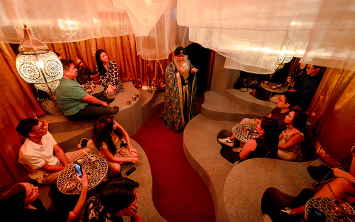 Guests watch a card performance in a tiered room at Wonderland Upside Down.