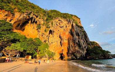 Railay Beach at sunset with limestone cliffs and tourists, Krabi, Thailand.