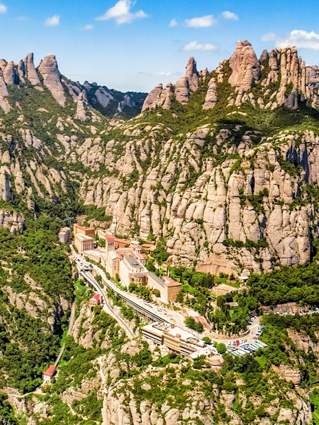 Aerial view of Montserrat mountain range near Barcelona, showcasing rugged peaks and lush landscape.