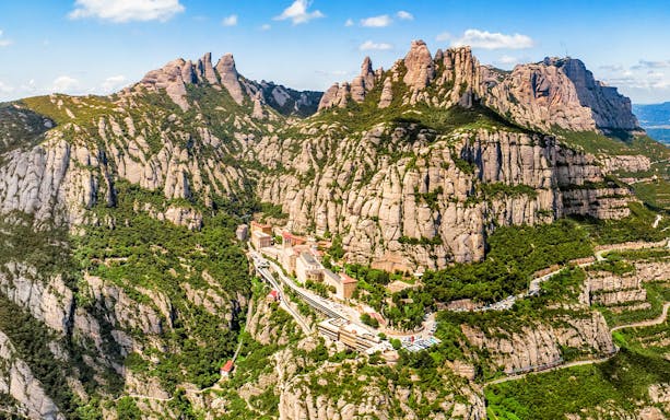 Aerial view of Montserrat mountain range near Barcelona, showcasing rugged peaks and lush landscape.