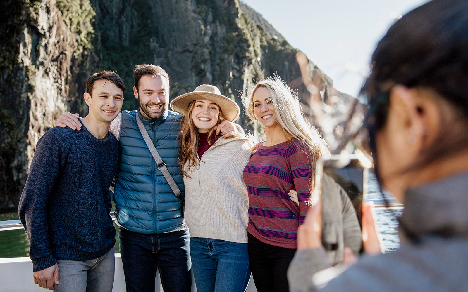 Group enjoying a 2-hour cruise on Milford Sound with scenic cliffs in the background.