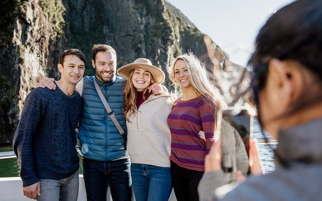 Group enjoying a 2-hour cruise on Milford Sound with scenic cliffs in the background.