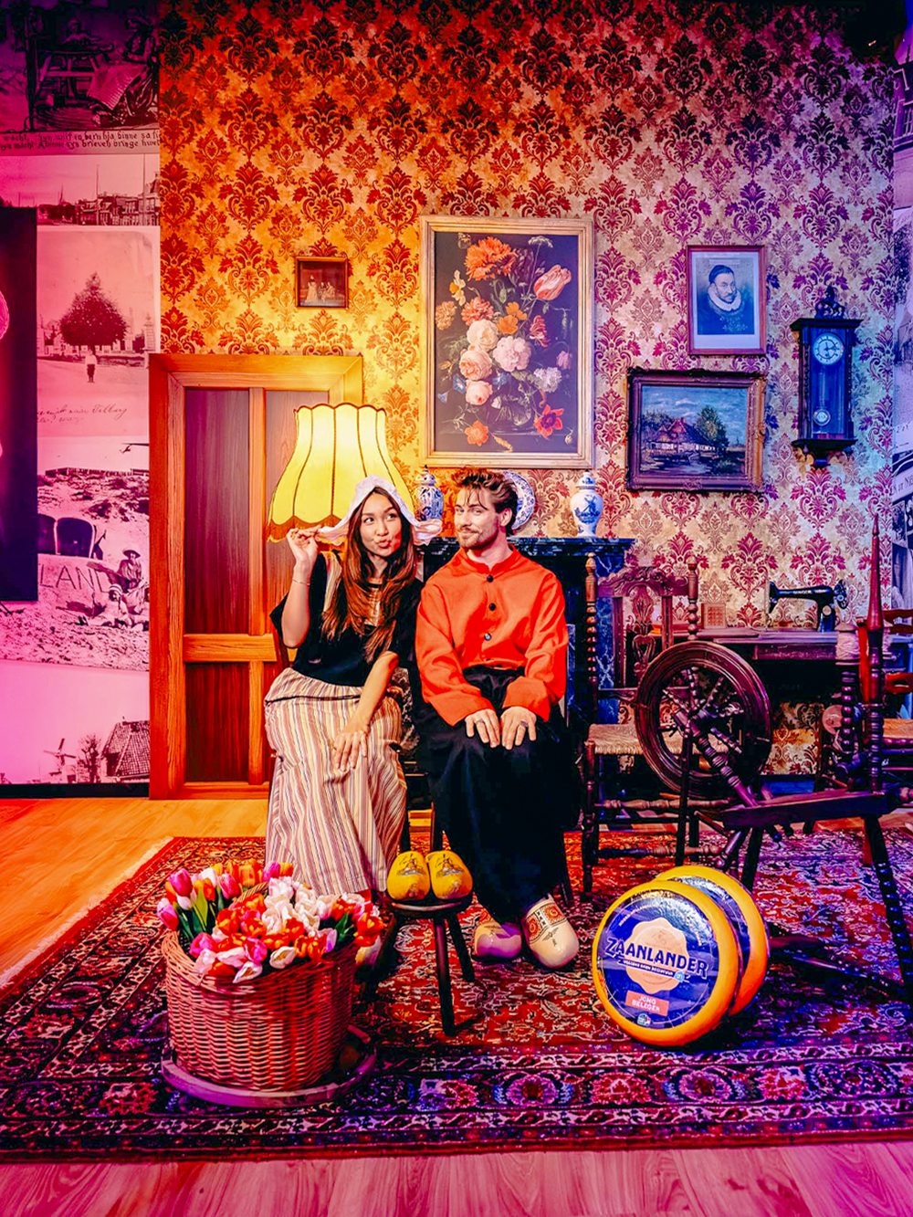 Guests in traditional Dutch attire with tulips and cheese in Holland-themed room.