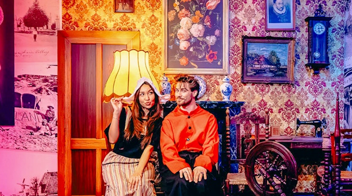 Guests in traditional Dutch attire with tulips and cheese in Holland-themed room.
