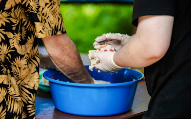 Hands shaping rice balls in a blue bowl at Bukit Elephant Park.