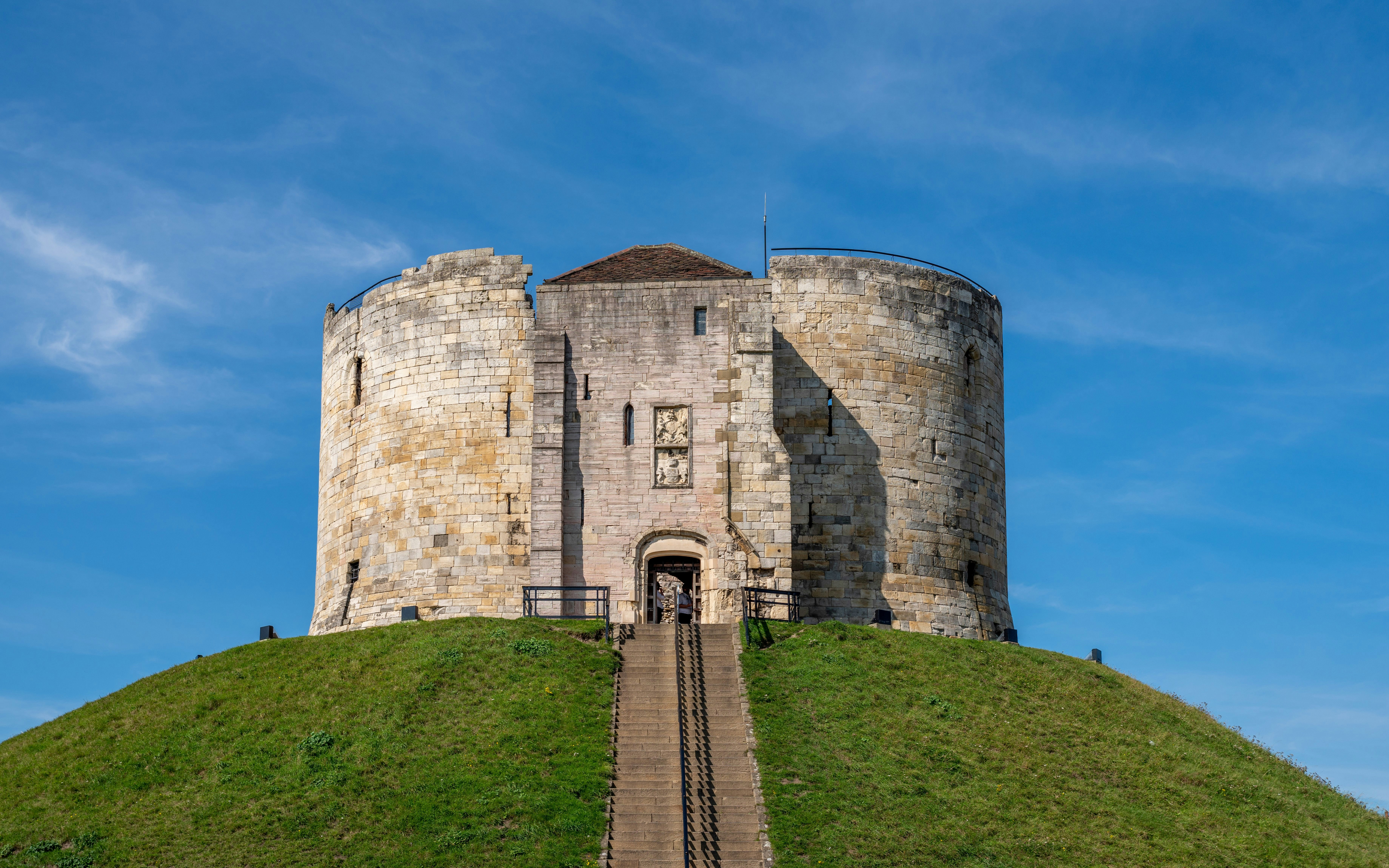 Clifford's Tower atop a grassy mound in York, showcasing Norman architecture.