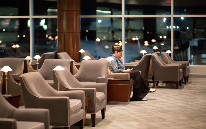 Woman reading in airport lounge with empty seats.
