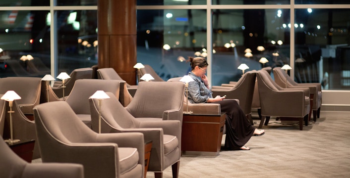 Woman reading in airport lounge with empty seats.