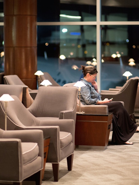 Woman reading in airport lounge with empty seats.