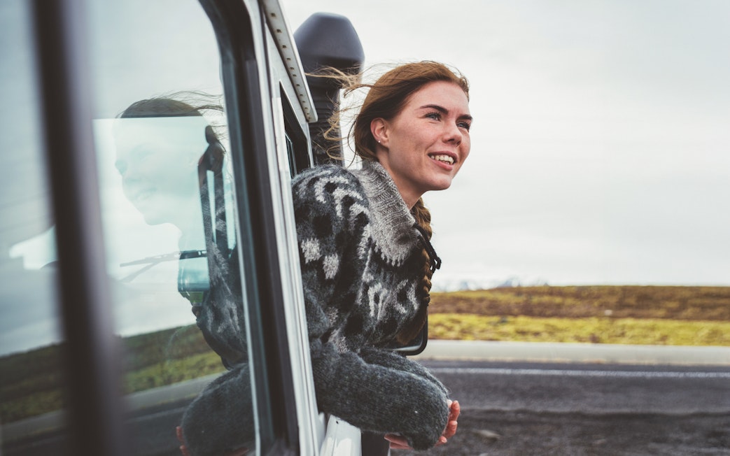 Woman looking out of a 4x4 SUV window at scenic landscape.