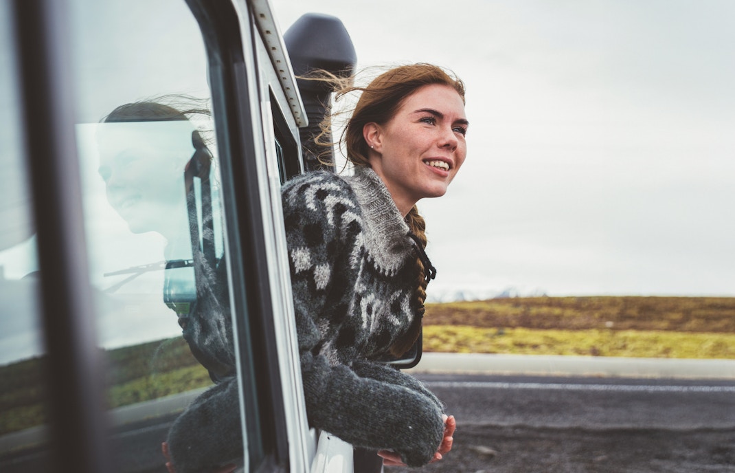 Woman looking out of a 4x4 SUV window at scenic landscape.