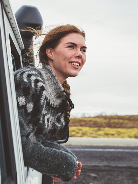 Woman looking out of a 4x4 SUV window at scenic landscape.