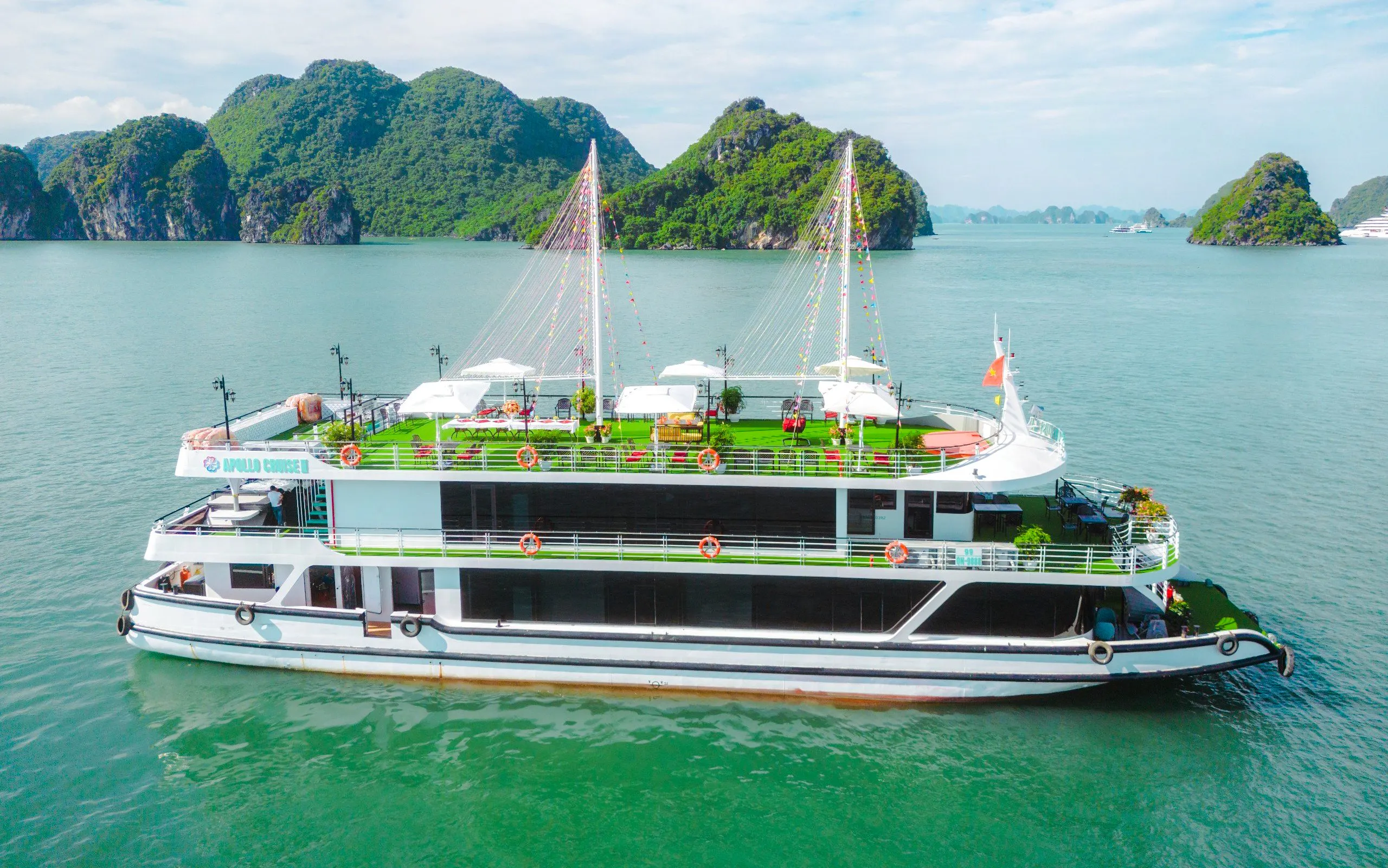 Apollo Cruise ship sailing in Ha Long Bay with limestone islands in the background.