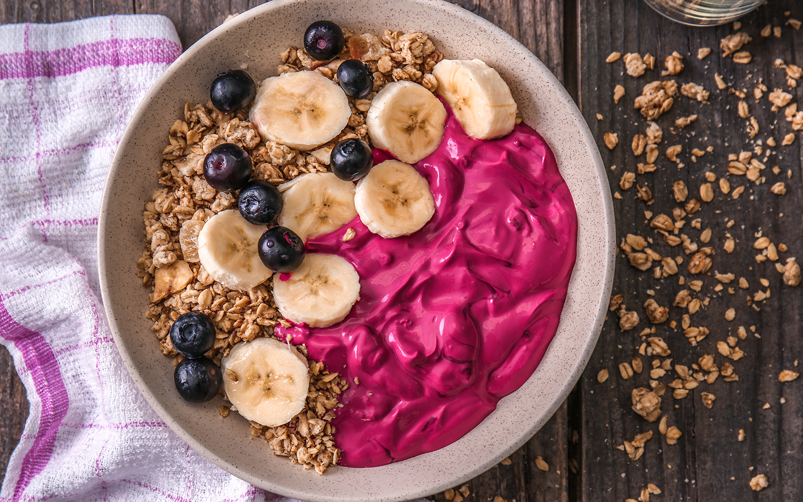 Bowl with tasty acai smoothie and fresh granola on wooden table