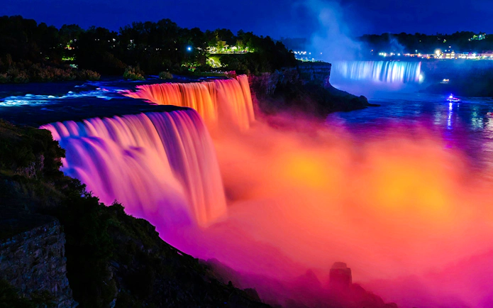 Niagara Falls illuminated at night with vibrant colors, USA.