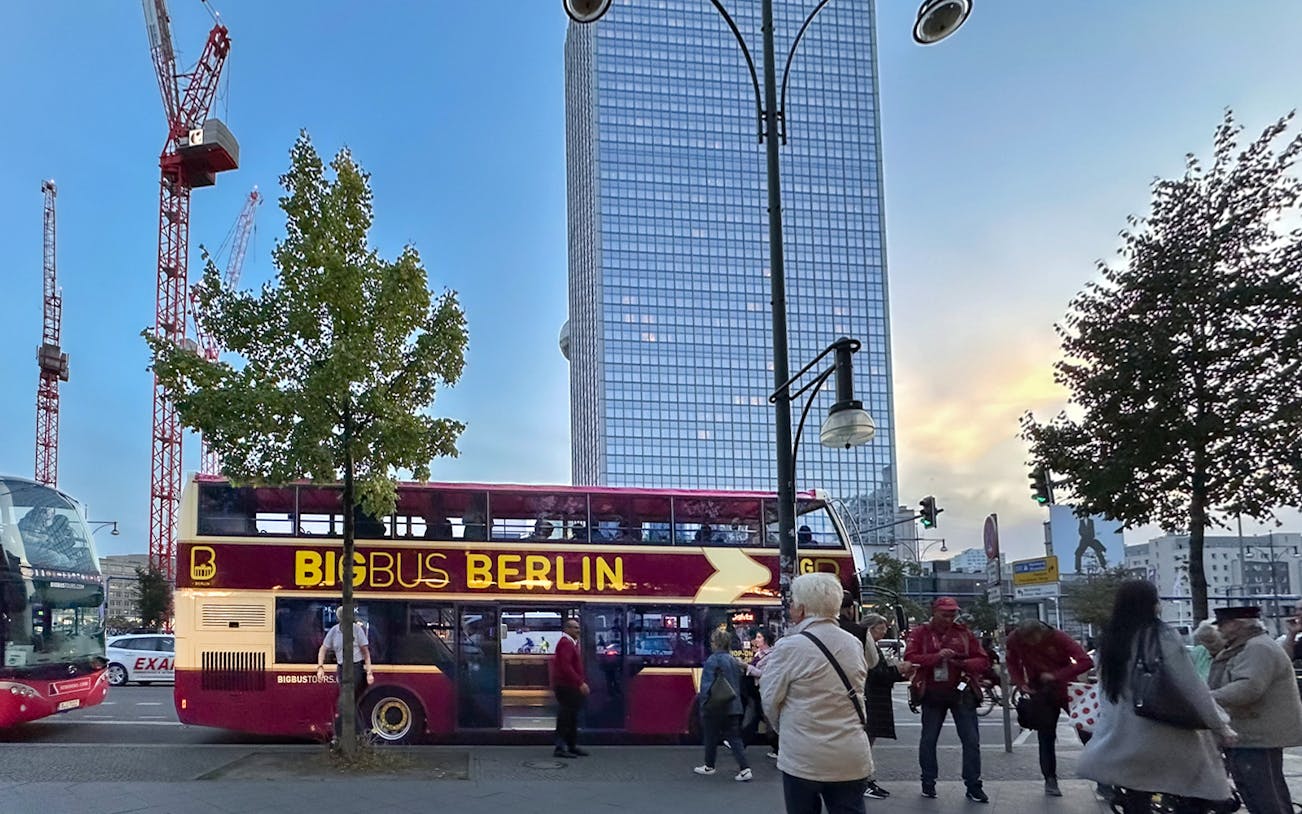 Double-decker bus on Stromma Evening Hop-On Hop-Off Berlin Tour with cityscape backdrop.