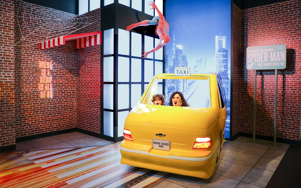 Spider-Man figure above yellow taxi at Madame Tussauds Dubai movie set.
