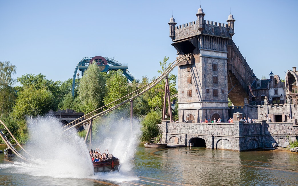 Visitors on a water ride at Efteling theme park, Netherlands, with a castle-like structure in the background.