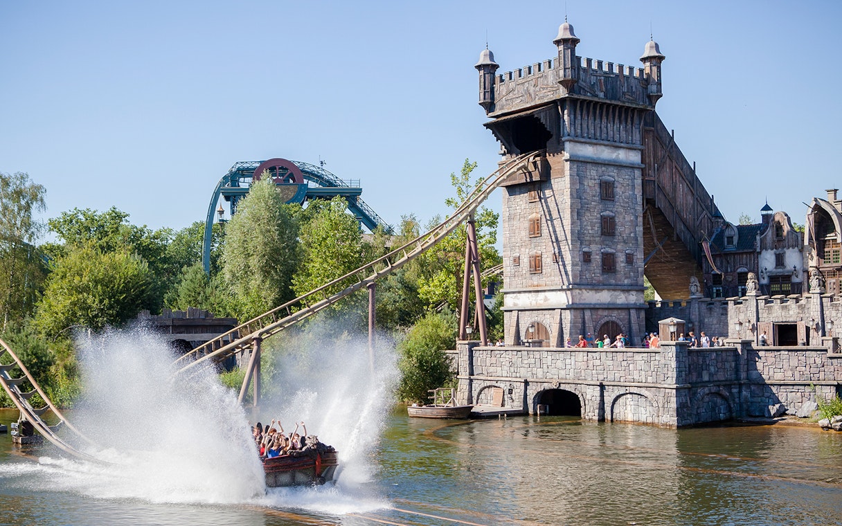 Visitors on a water ride at Efteling theme park, Netherlands, with a castle-like structure in the background.