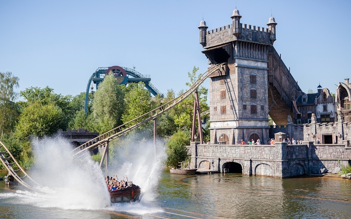 Visitors on a water ride at Efteling theme park, Netherlands, with a castle-like structure in the background.