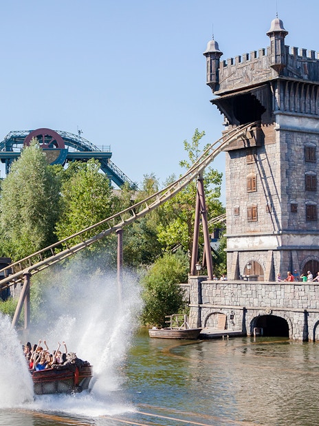 Visitors on a water ride at Efteling theme park, Netherlands, with a castle-like structure in the background.