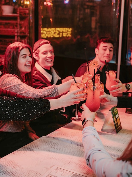 Participants toasting with Hungarian cocktails at a lively Budapest bar.