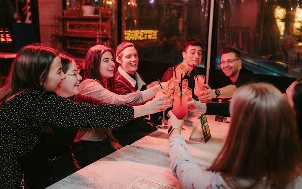 Participants toasting with Hungarian cocktails at a lively Budapest bar.