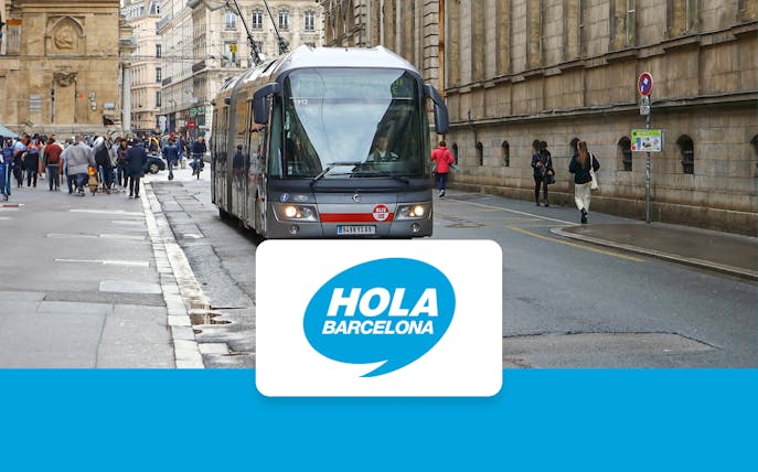 Tram on a busy street in Barcelona with Hola Barcelona logo.