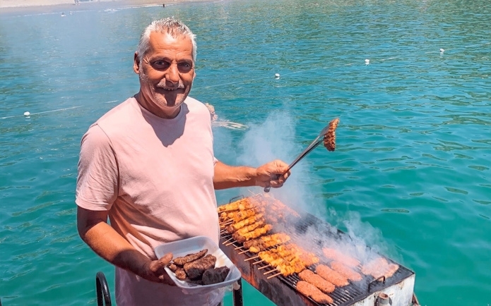 Man grilling kebabs on a boat during Alanya Relaxing Boat Tour.