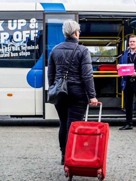 Tourist with luggage assisted by staff at Reykjavik Keflavik airport shuttle.