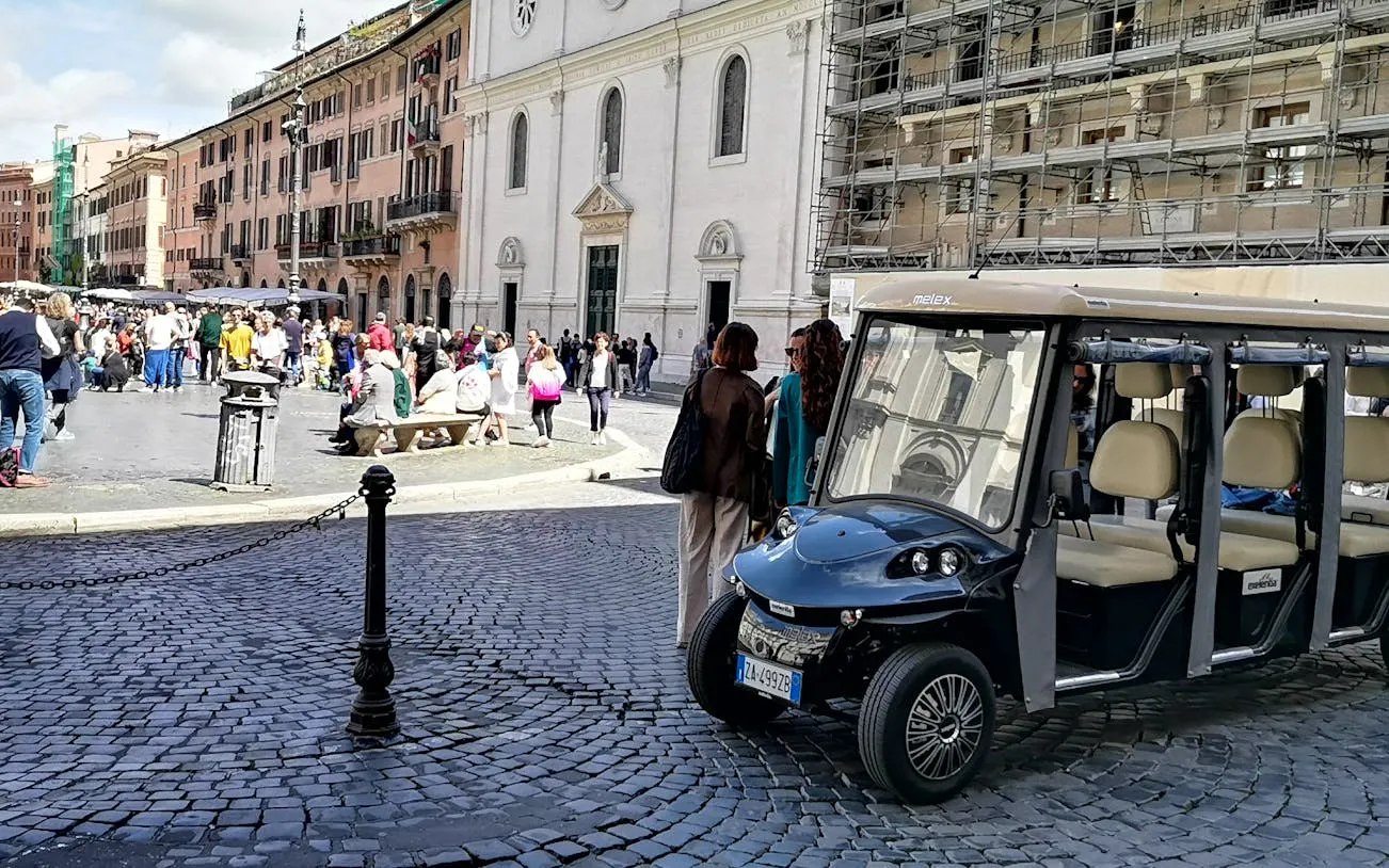 Golf cart parked in a busy Roman square during a night tour.