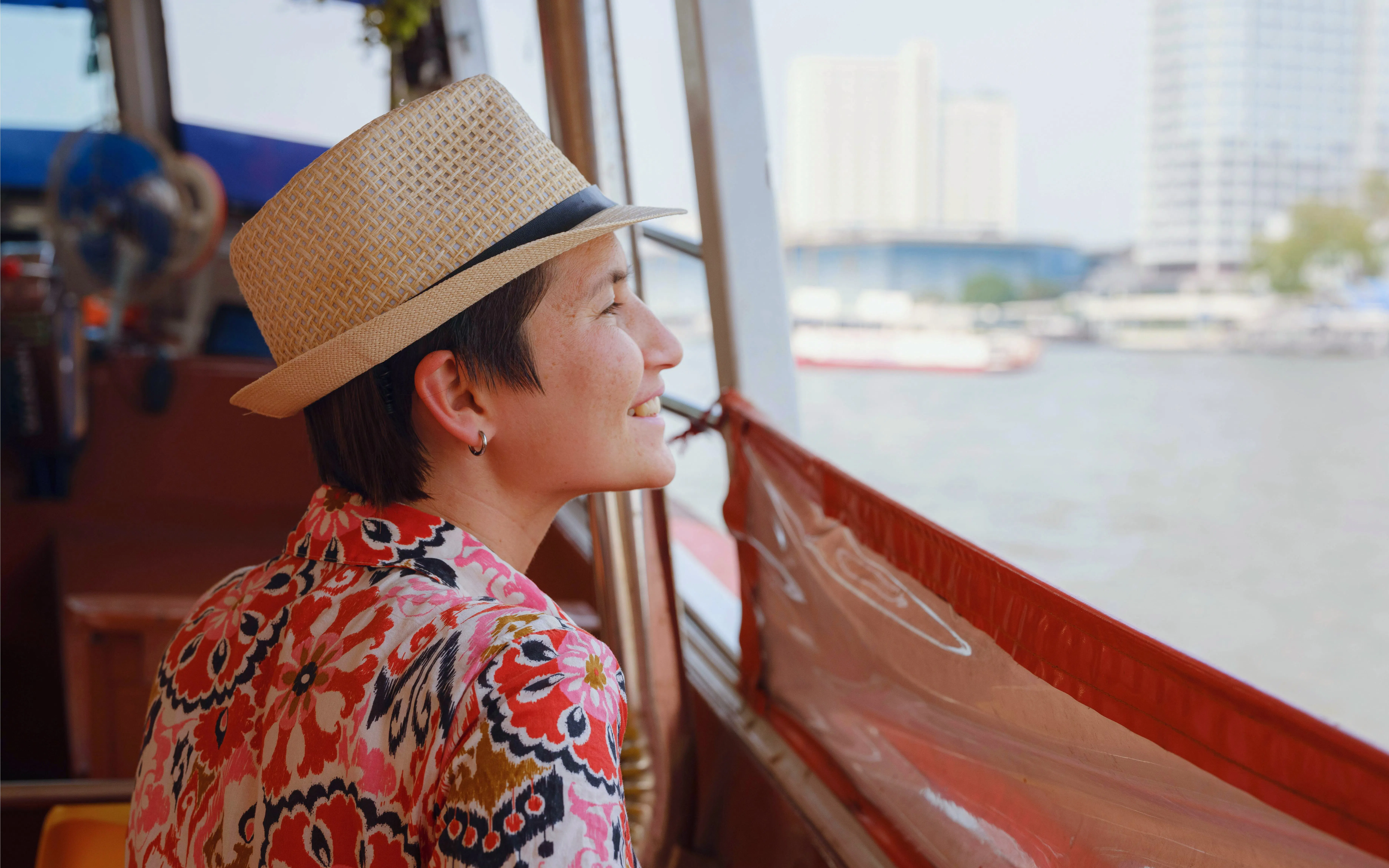 Tourist enjoying river view from cruise boat in city.