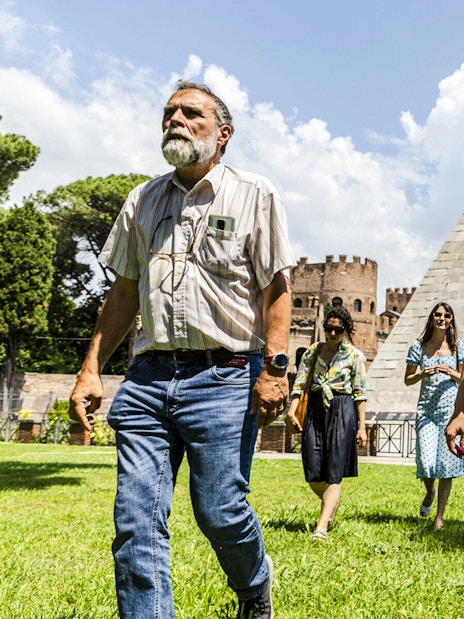 Tourists walking near the Pyramid of Cestius during the Taste of Testaccio Food & Market Tour in Rome.