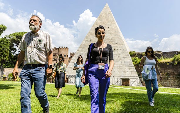 Tourists walking near the Pyramid of Cestius during the Taste of Testaccio Food & Market Tour in Rome.