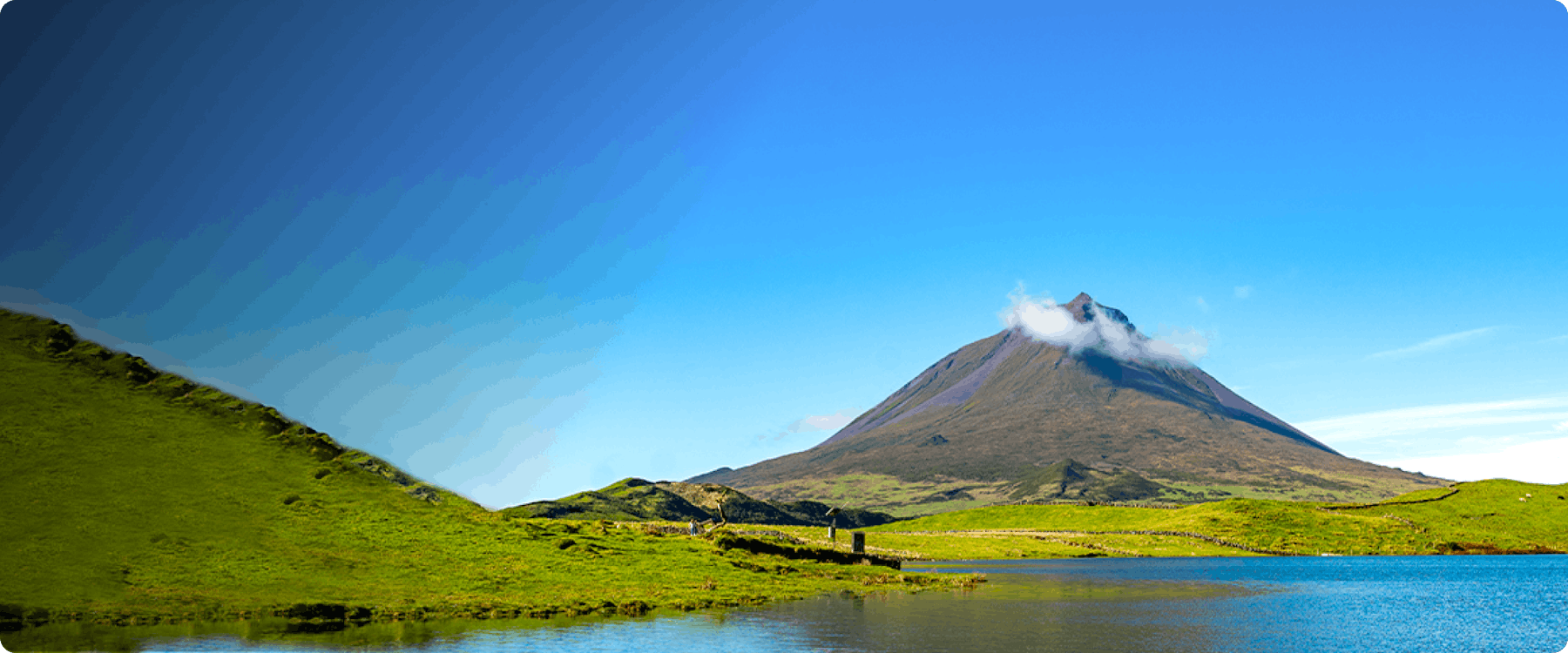 Mountain landscape with a lake in Ponta Delgada, Azores, under a clear blue sky.