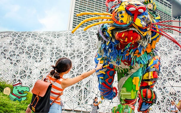 Person interacting with colorful recycled sculpture at Ransack Puzzle Hunt: The Meltdown Menace.