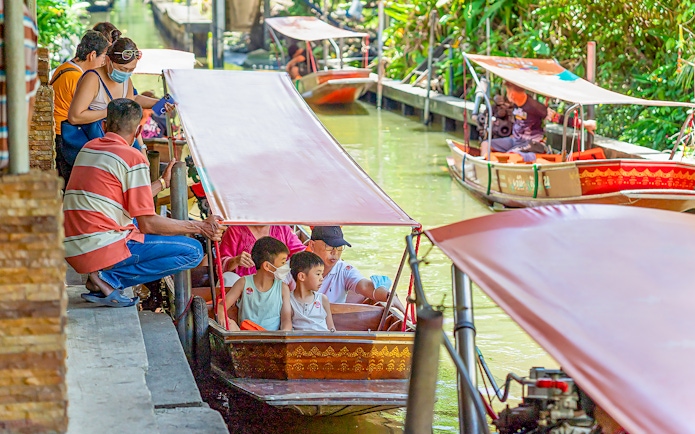 Visitors on a boat tour at Damnoen Saduak Floating Market, Thailand.