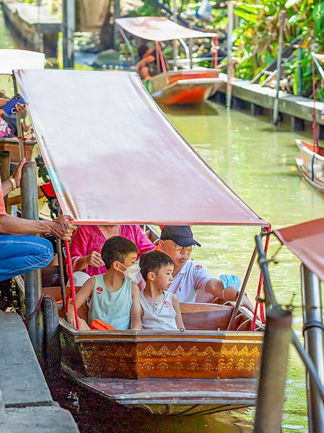 Visitors on a boat tour at Damnoen Saduak Floating Market, Thailand.