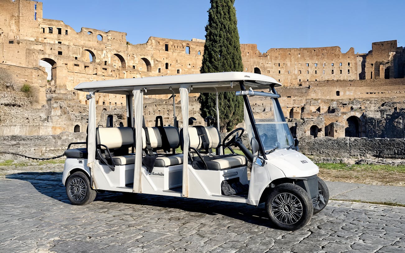 Golf cart parked on cobblestones near the Colosseum in Rome.