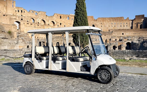 Golf cart parked on cobblestones near the Colosseum in Rome.