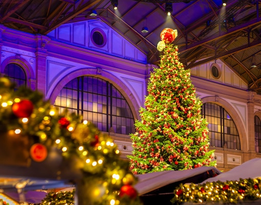 Indoor Christmas market with a large decorated tree and festive lights.